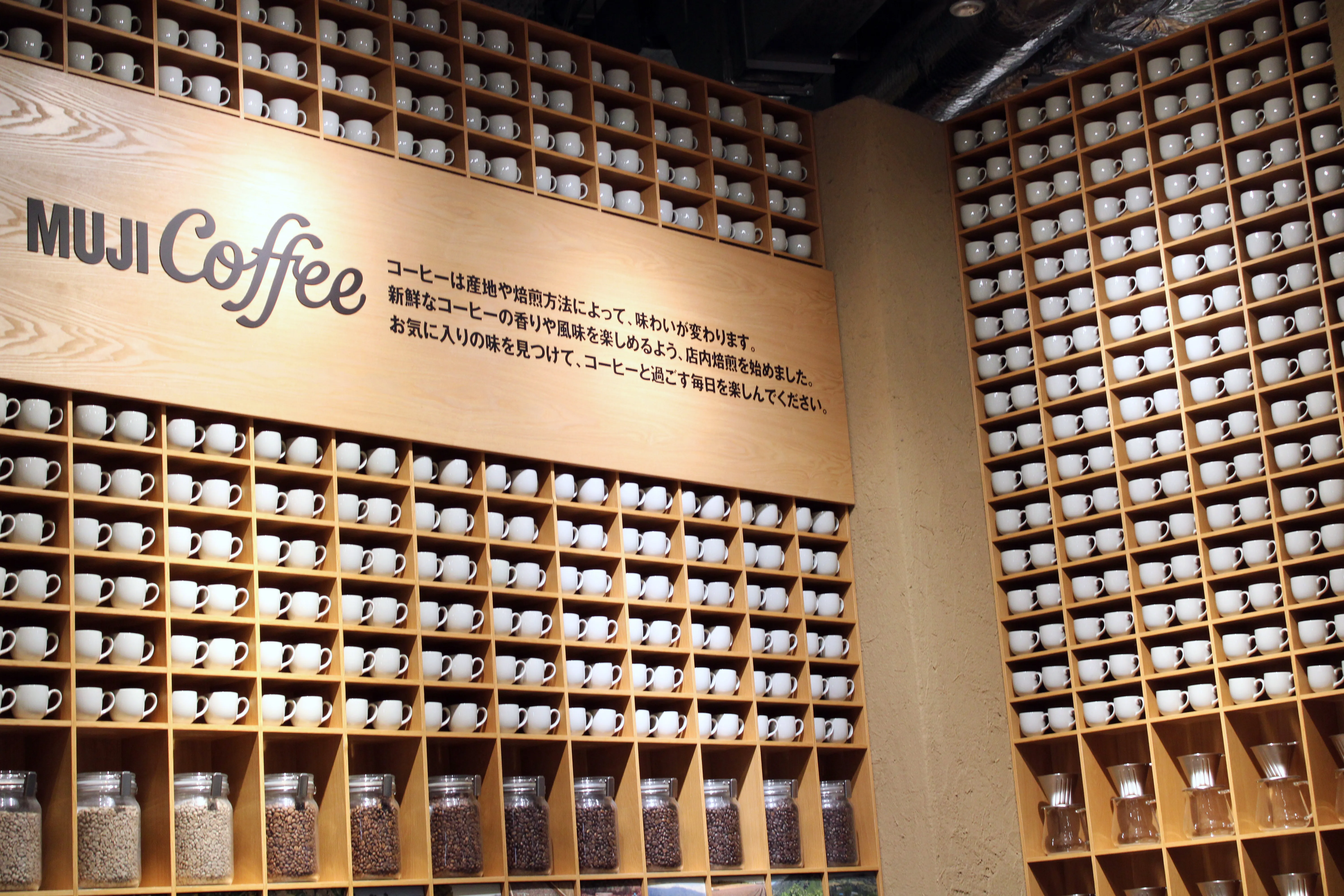 Muji's big walls lined to the brim with coffee cups with a sign saying "Muji Coffee" and a bunch of Japanese I can only read small parts of like the three times it says "koohii" which means coffee if that's not obvious