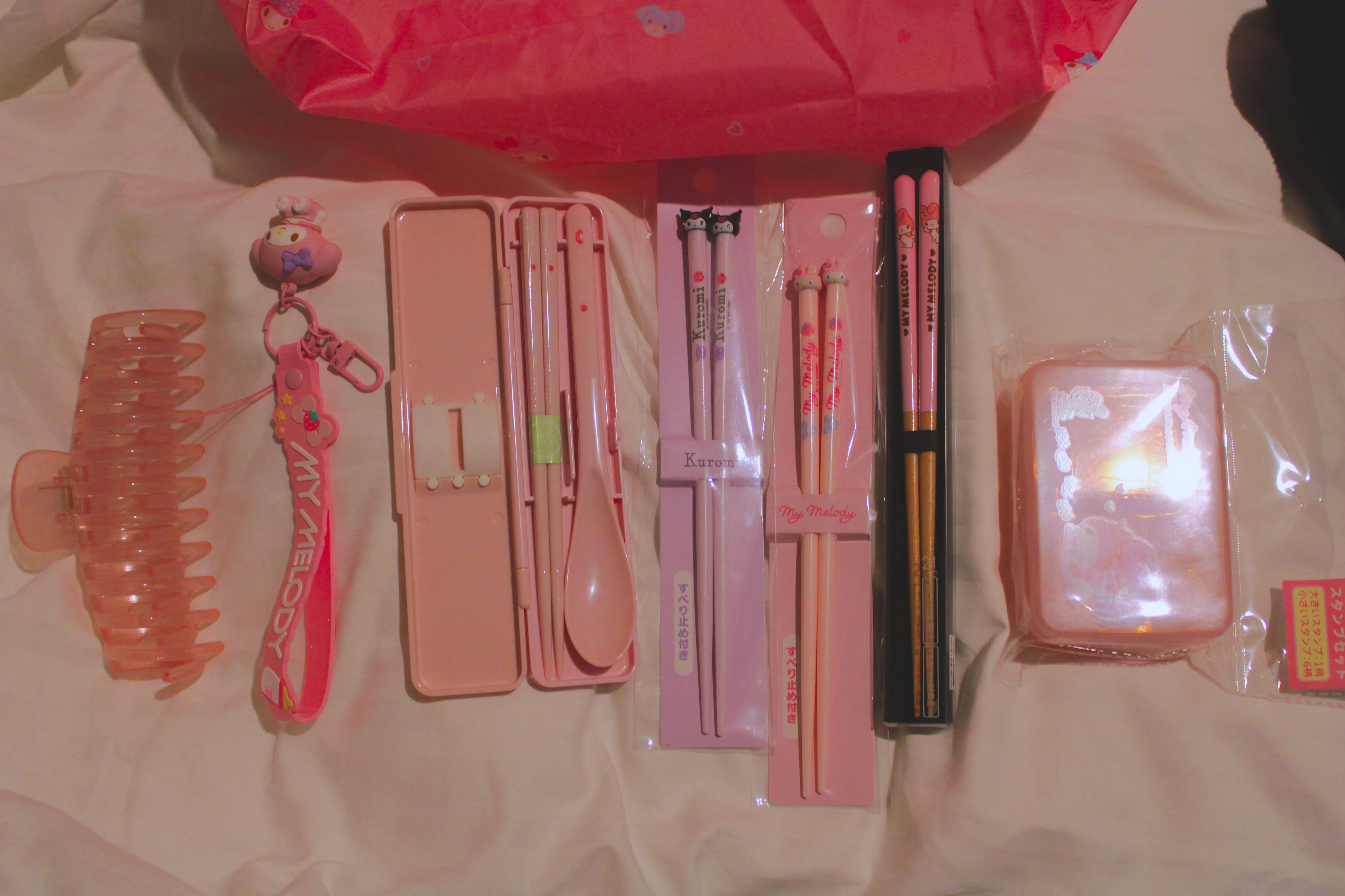 My day 1 Sanrio store haul, which consists of four sets of chopsticks all My Melody except one Kuromi, a My Melody stamp set, and a My Melody wrist clip, also the hair clip my mum bought me is in the photo as well but it&#x27;s not from the Sanrio store