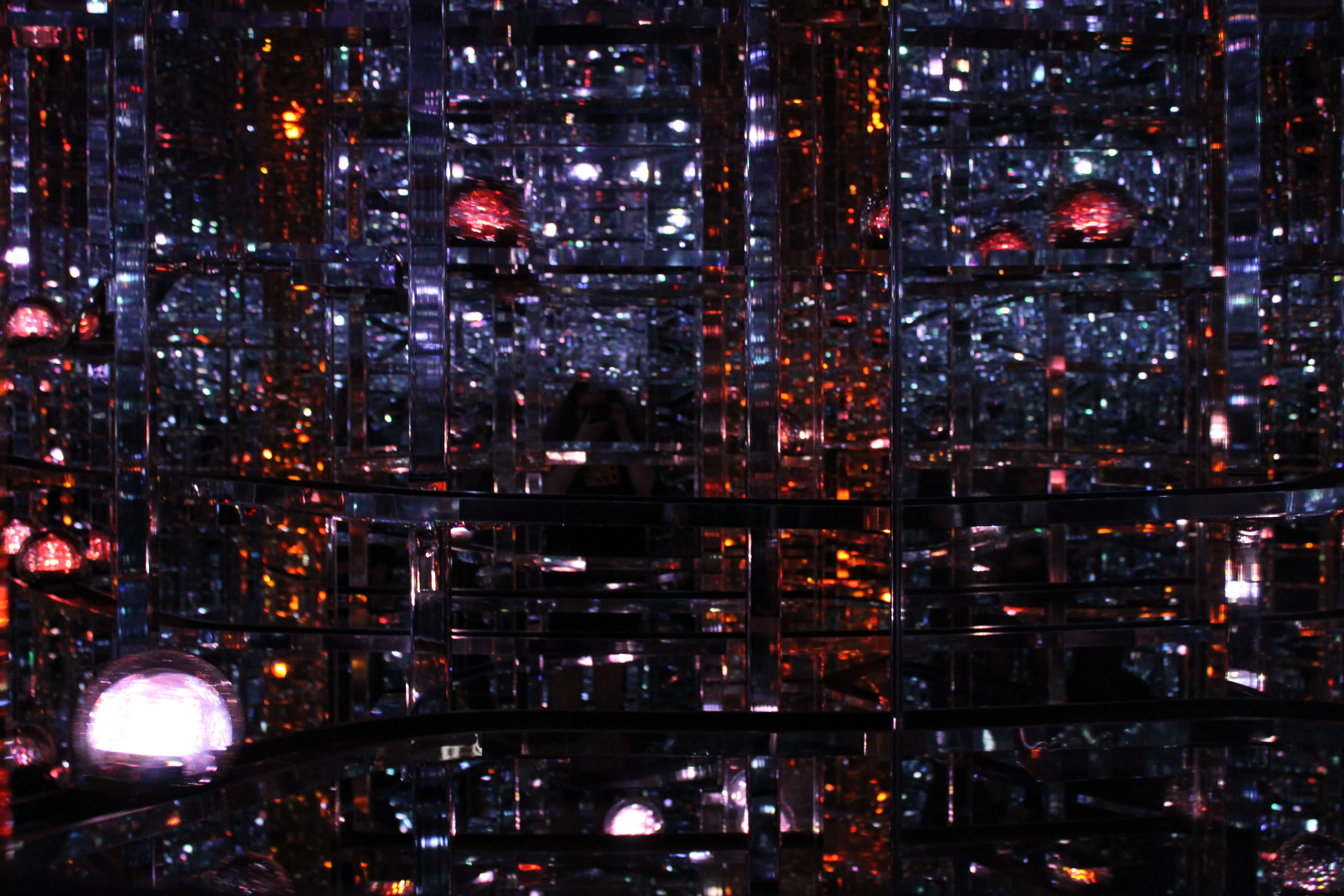 Balls of light going past on tracks, everything dark except for some orange lights