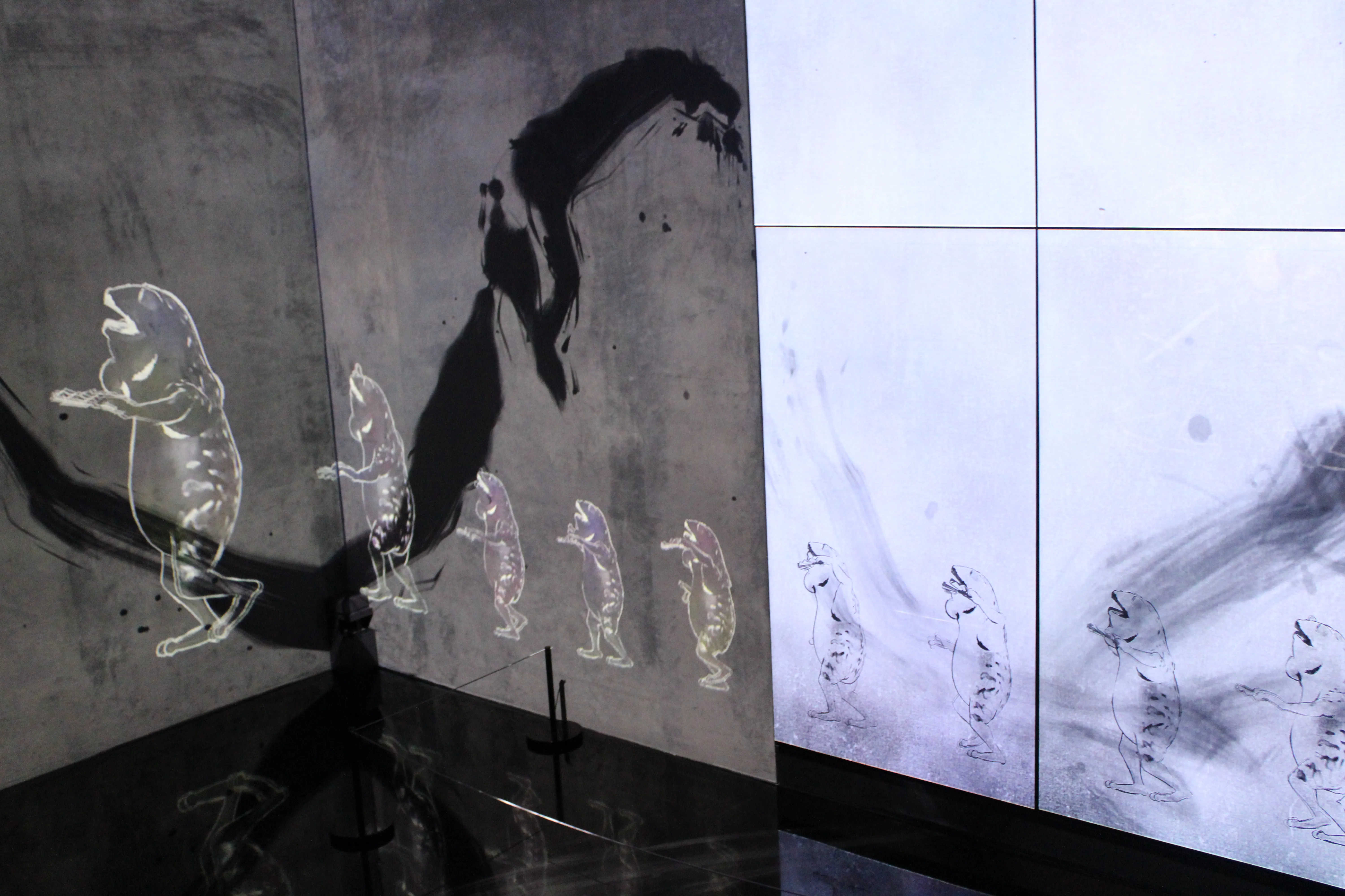 A shot after a show of frogs going in circles in TeamLab. They are now exiting the screen they were doing circles in (with frogs playing instruments on the walls) and are now growing back to their normal wall size